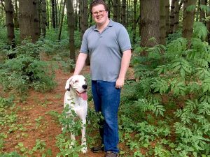 Davis Breen standing in the woods with his dog.