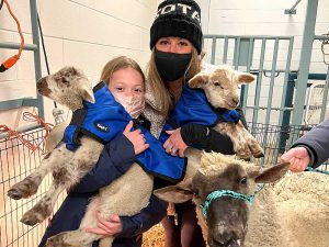 Megan with her daughter holding sheep.