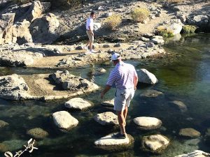 Steve Finkelstein walking over rocks in a a stream.